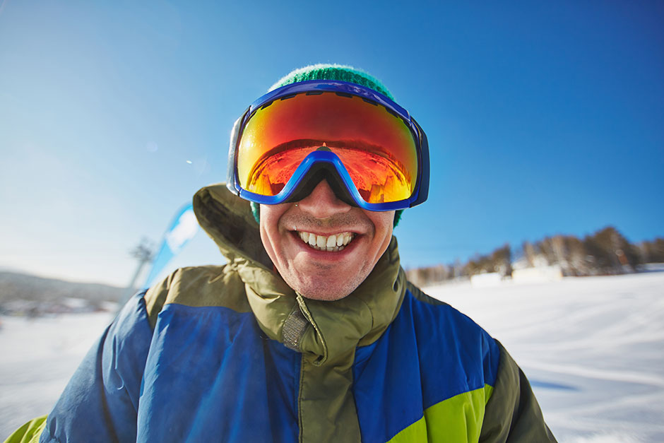 Cerca de las gafas de esquí de un hombre con el reflejo de las montañas  nevadas